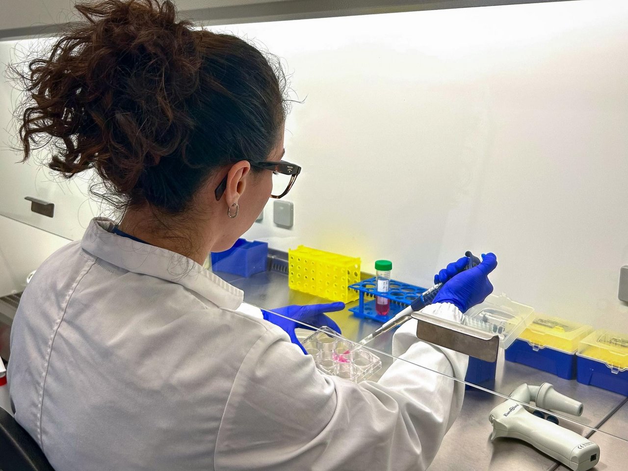 Ricercatrice in camice utilizza una cappa biologica in laboratorio